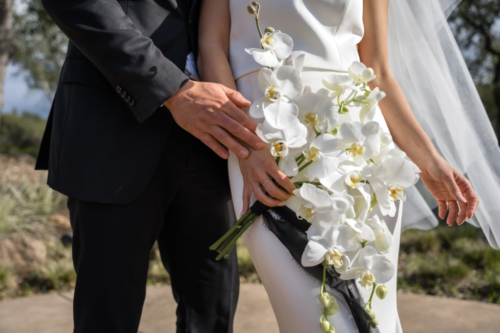 Bride Holding a Bouquet of White Orchids and Posing with Her Groom