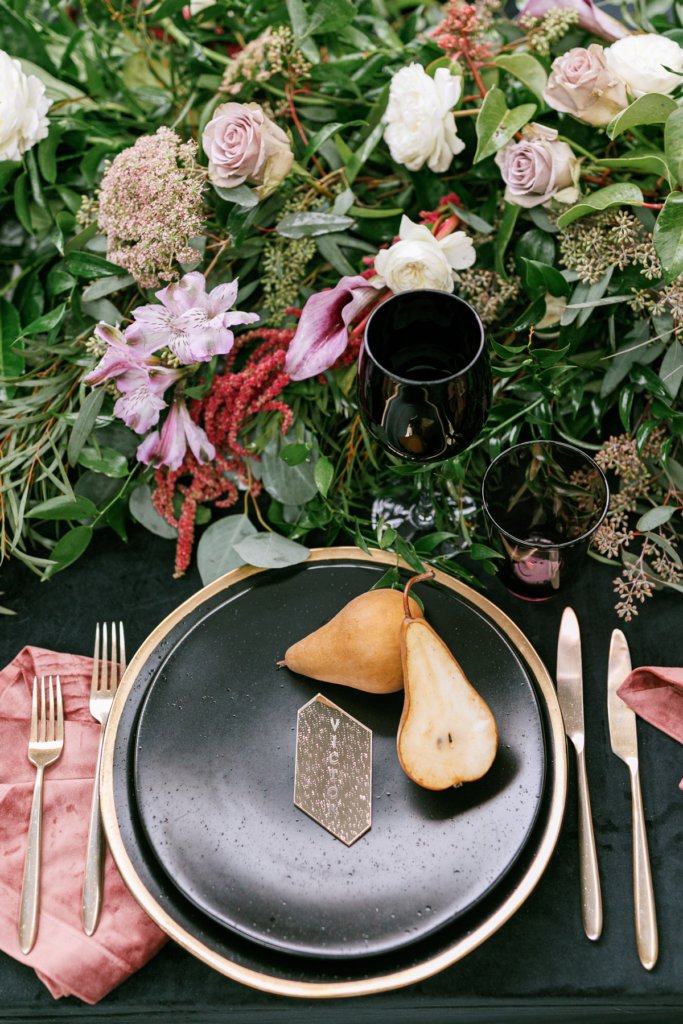 Lush Winter Wedding Table with a Full Garland, Black and Gold Place Settings and Pops of Rose and Lilac